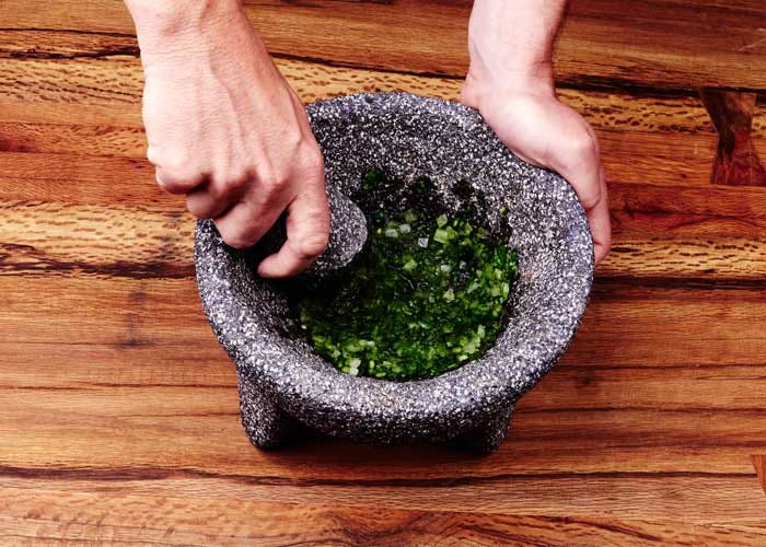 Ground cilantro and onion in a molcajete
