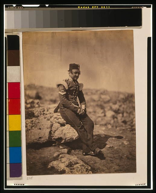 black and white photo of a soldier in uniform sitting on a rock