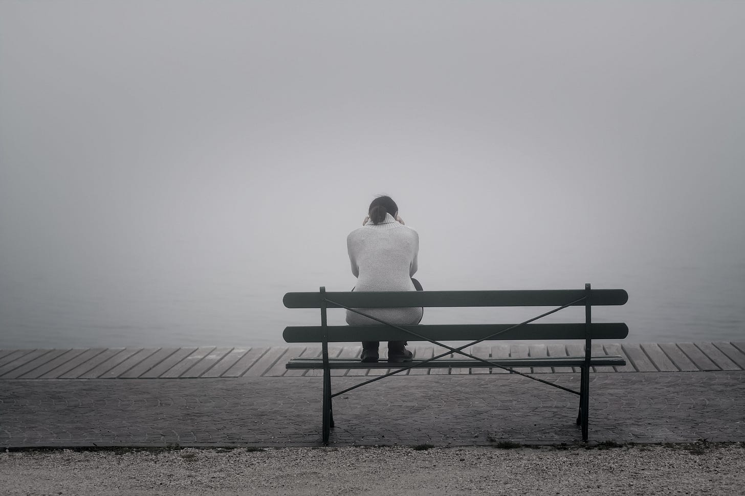 lonely woman at beach sitting on a bench