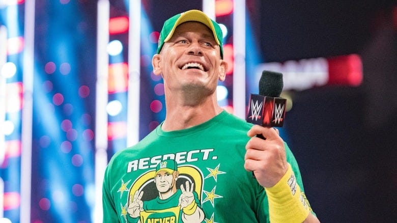 John Cena smiling while holding a WWE microphone