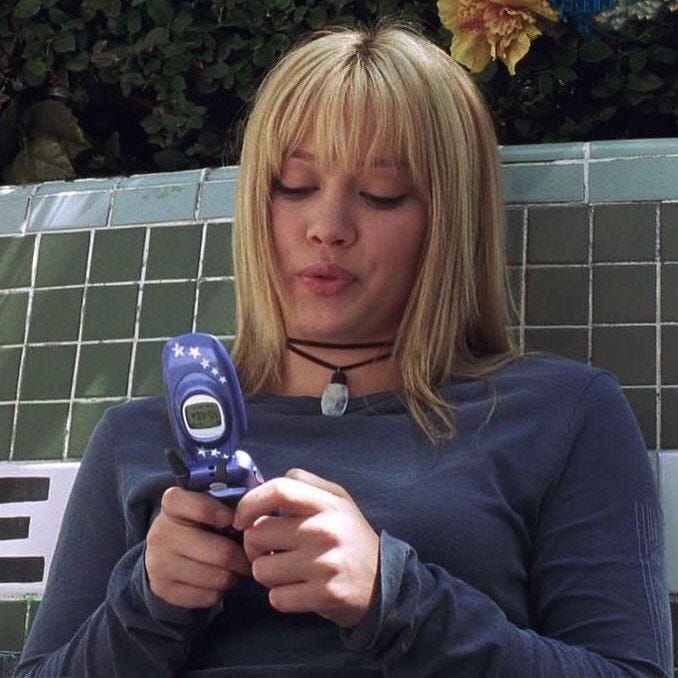 This may contain: a woman sitting on a bench looking at her cell phone while holding it in her hand