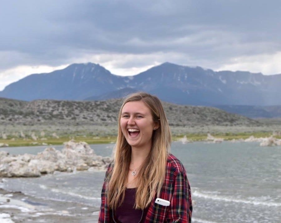 young woman laughing outdoors near a lake and mountains