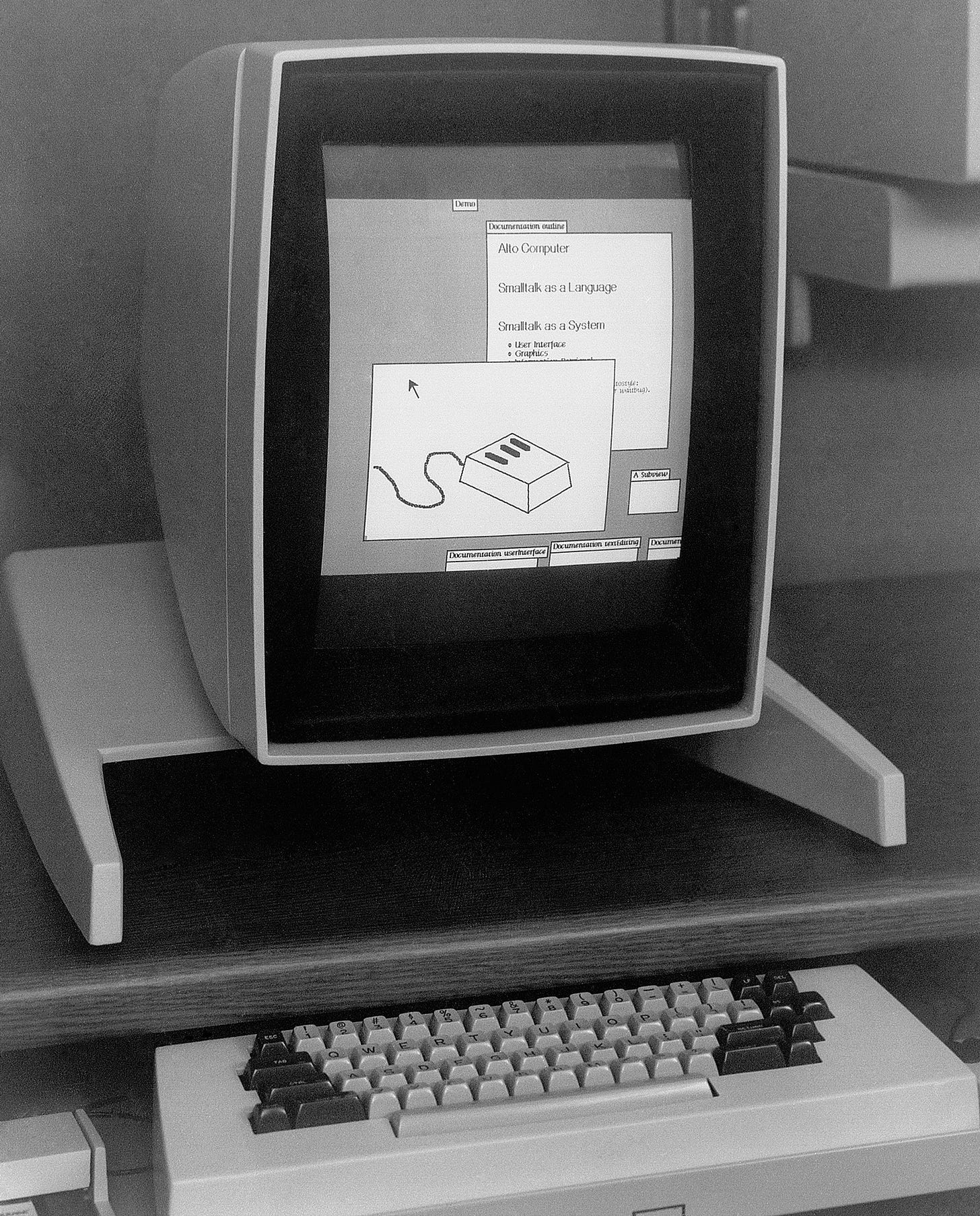 A black-and-white vertical display on a desk above a keyboard and mouse