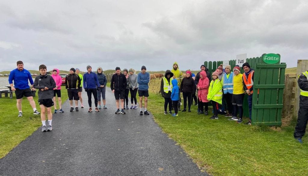 Group photo, lots of people looking cold and trying to shelter from the wind just before the parkrun start