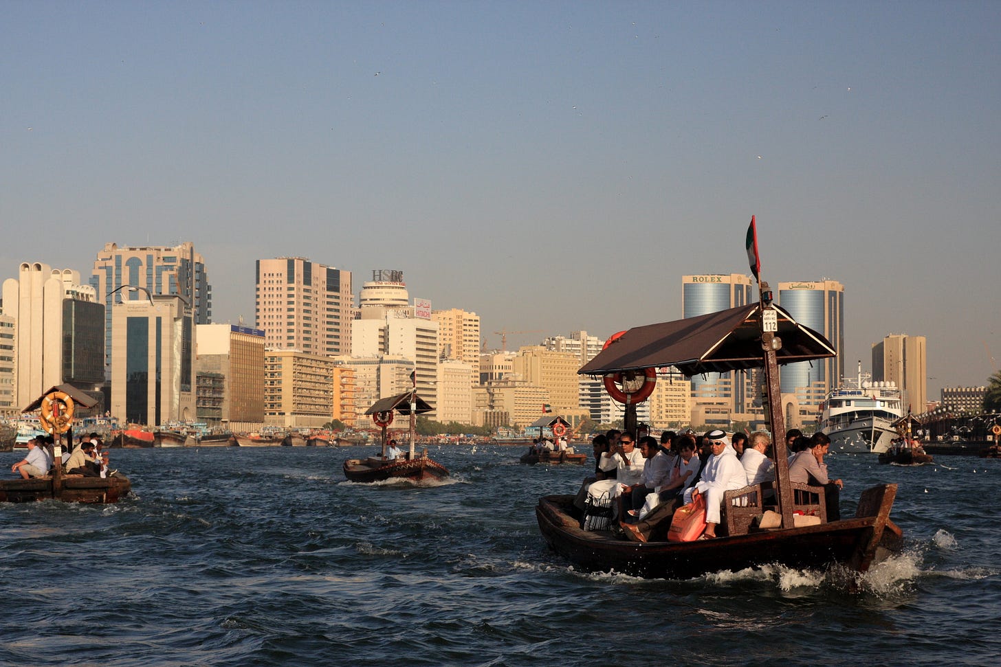 photo of the Dubai creek showing small wooden traditional boats carrying people and a view of the Deira side of Dubai's skyline. photo of the Dubai creek showing small wooden traditional boats carrying people and a view of the Deira side of Dubai's skyline.