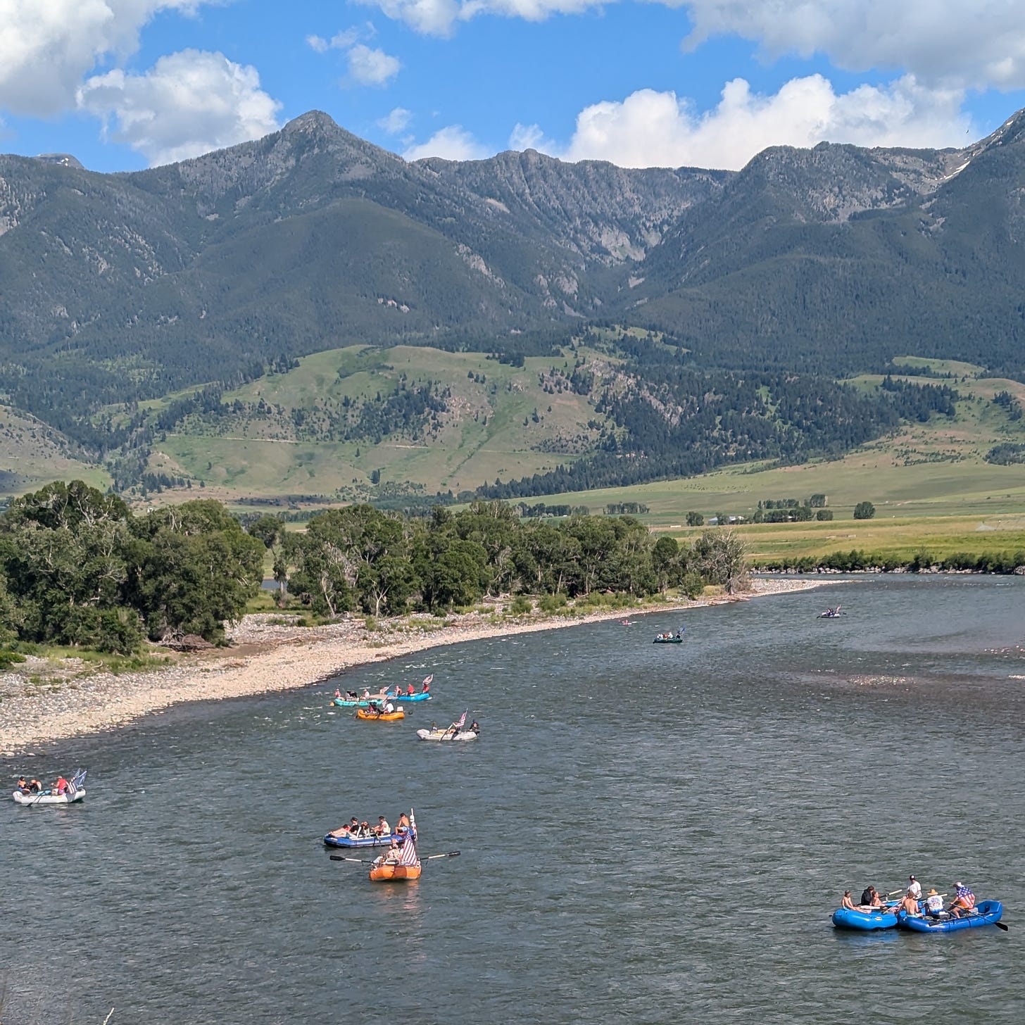 Flotilla of rafts with giant American flags, playing music out of speakers, floating past Mallard’s Rest fishing access on the 4th of July.