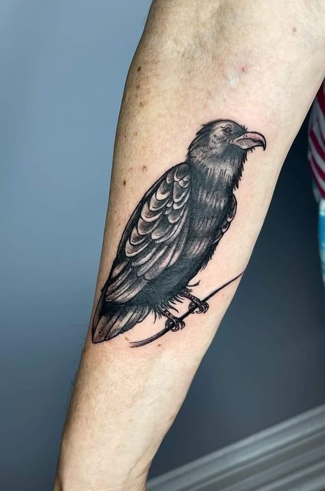 raven tattoo on an inner forearm