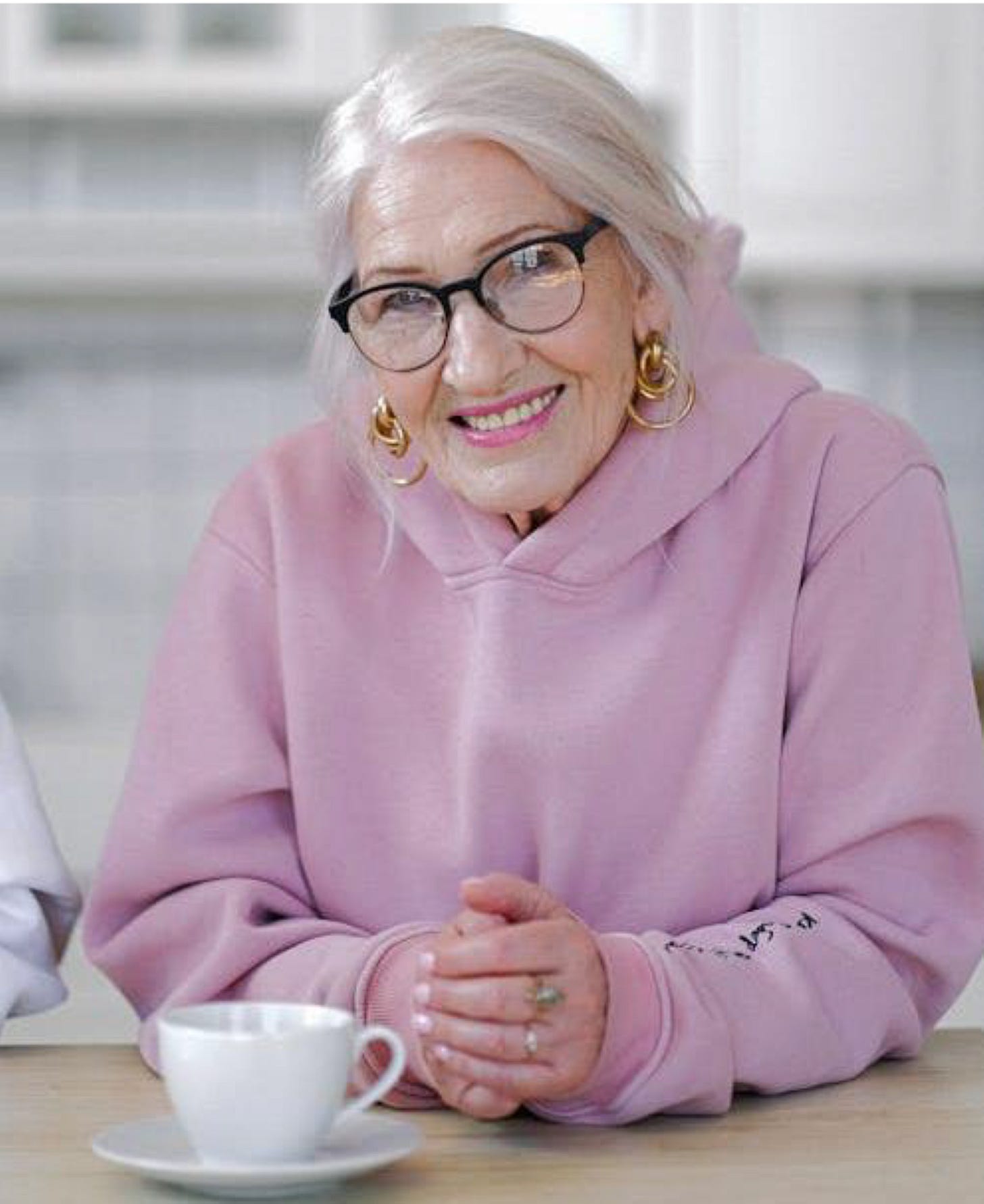 White-haired elderly woman at table with tea cup