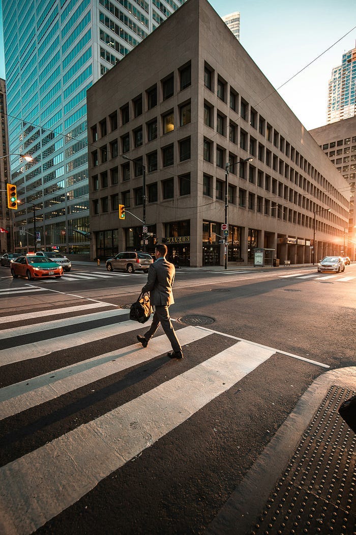 man in suit walking in sunshine in city.