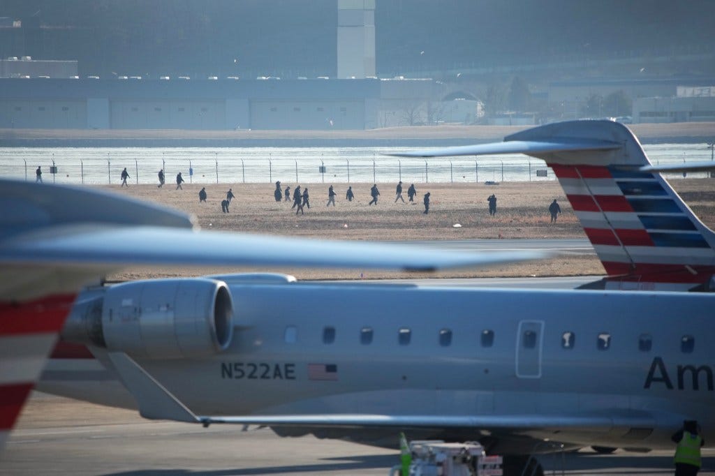  Investigators walk the grounds of the Reagan National Airport as they work after the crash last night of the American Airlines plane on the Potomac River as it approached the Reagan National Airport in Arlington, Virginia, on Thursday.