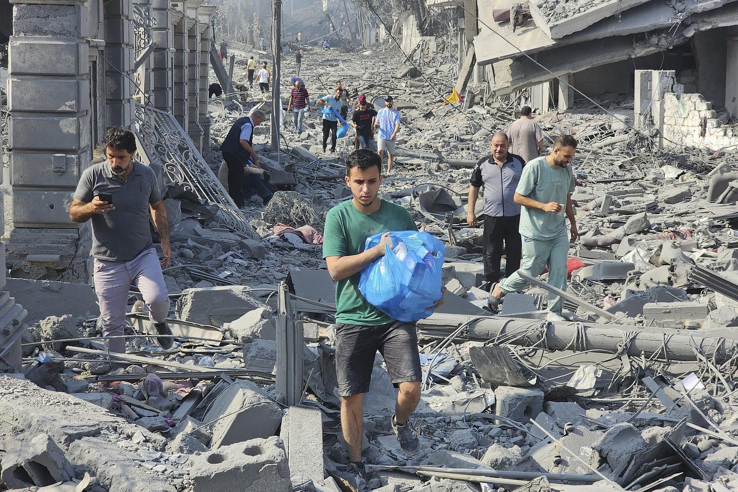 Palestinians walk through the rubble of buildings destroyed by Israeli airstrikes in Gaza City.