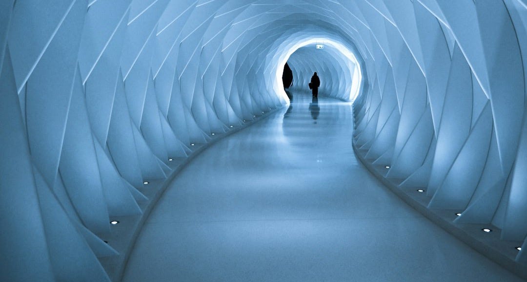 two people are walking through a tunnel in the snow