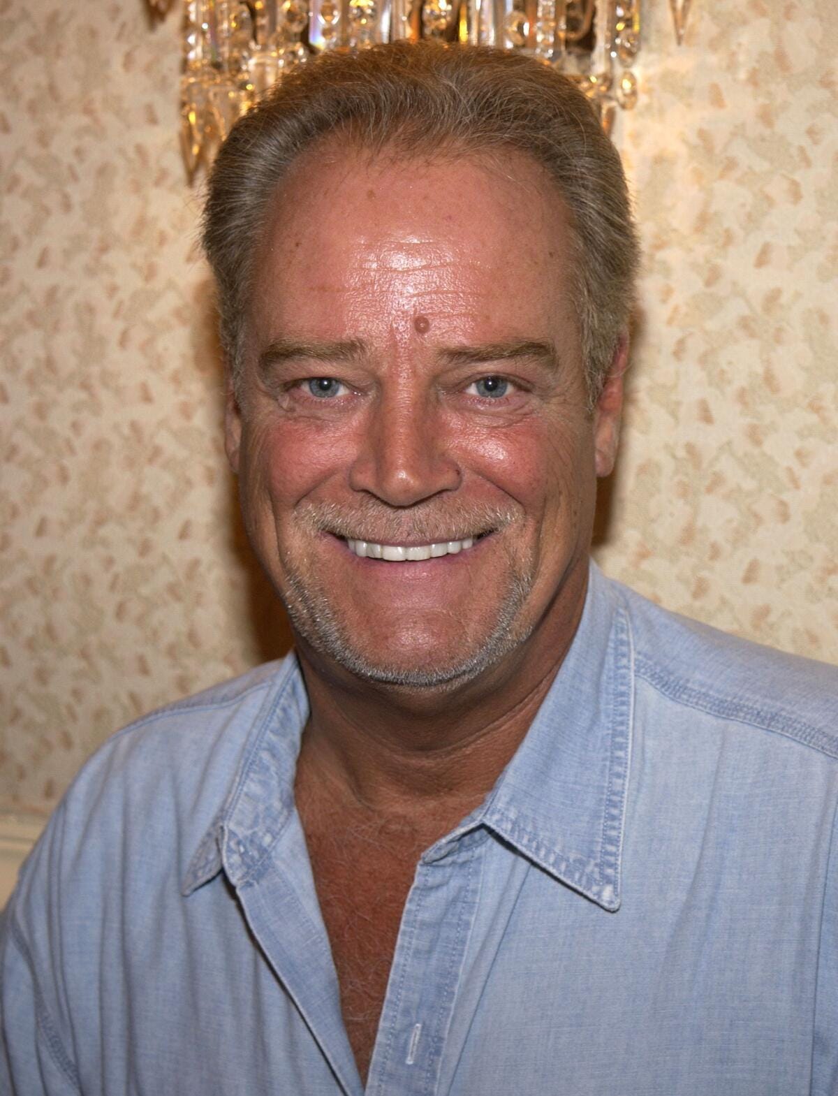 Ron Hale smiling in a light blue denim button-down shirt