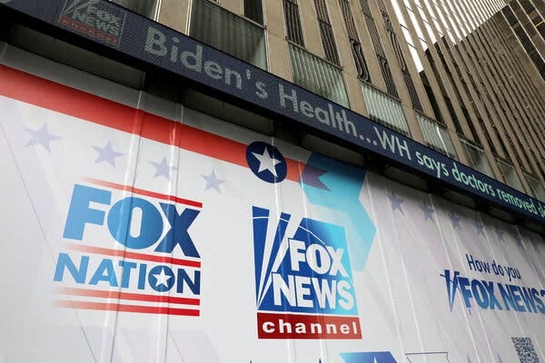 The exterior of the Fox News headquarters in New York City, with the red-white-and-blue logos of Fox Nation and The Fox News Channel prominently displayed. 
