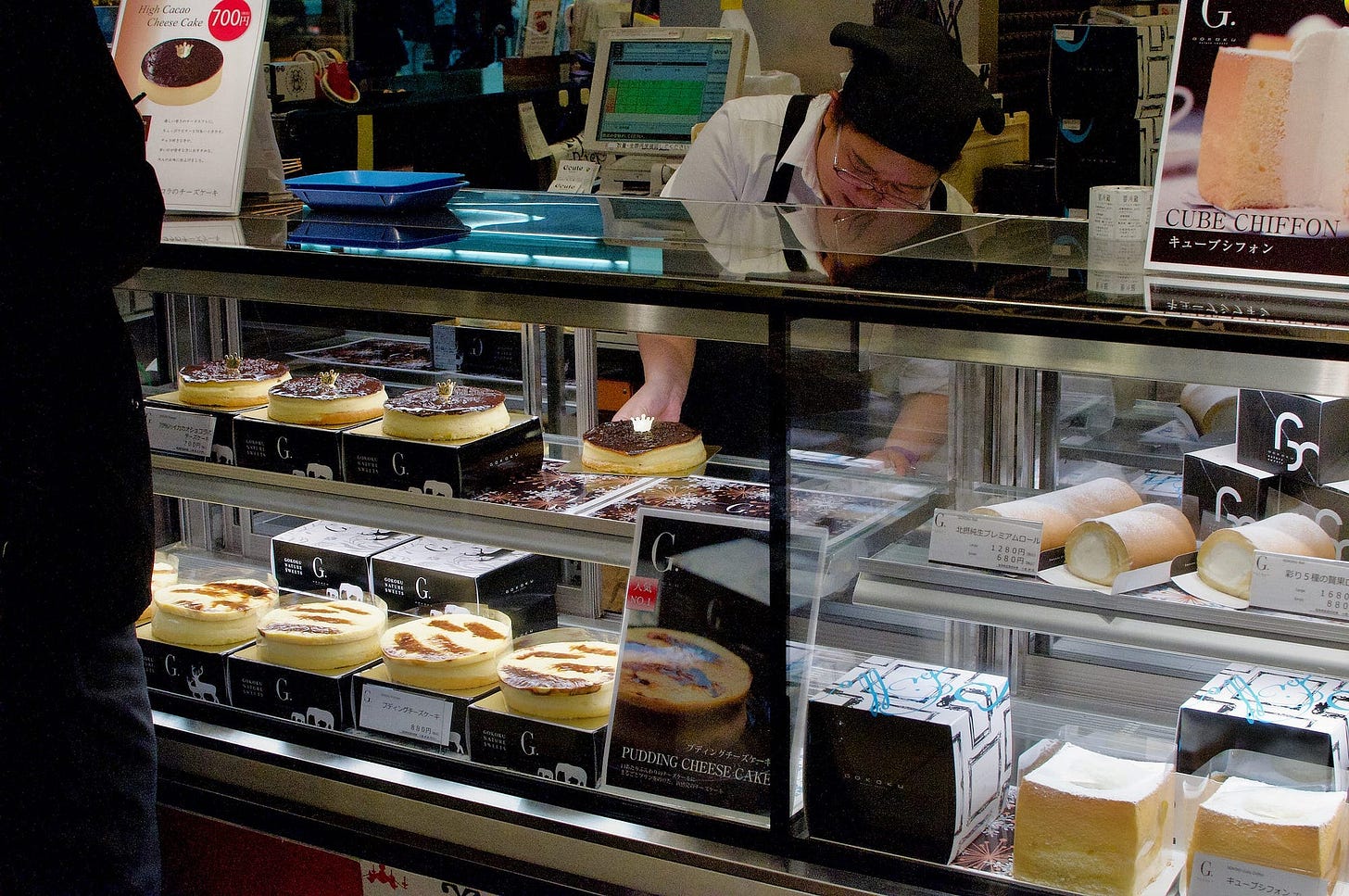 Person removing a pudding cheesecake from display case, photo by Juan Aguilera.