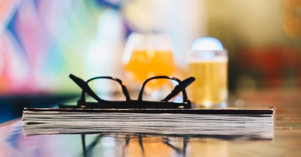 black eyeglasses on closed book on table selective focus photography