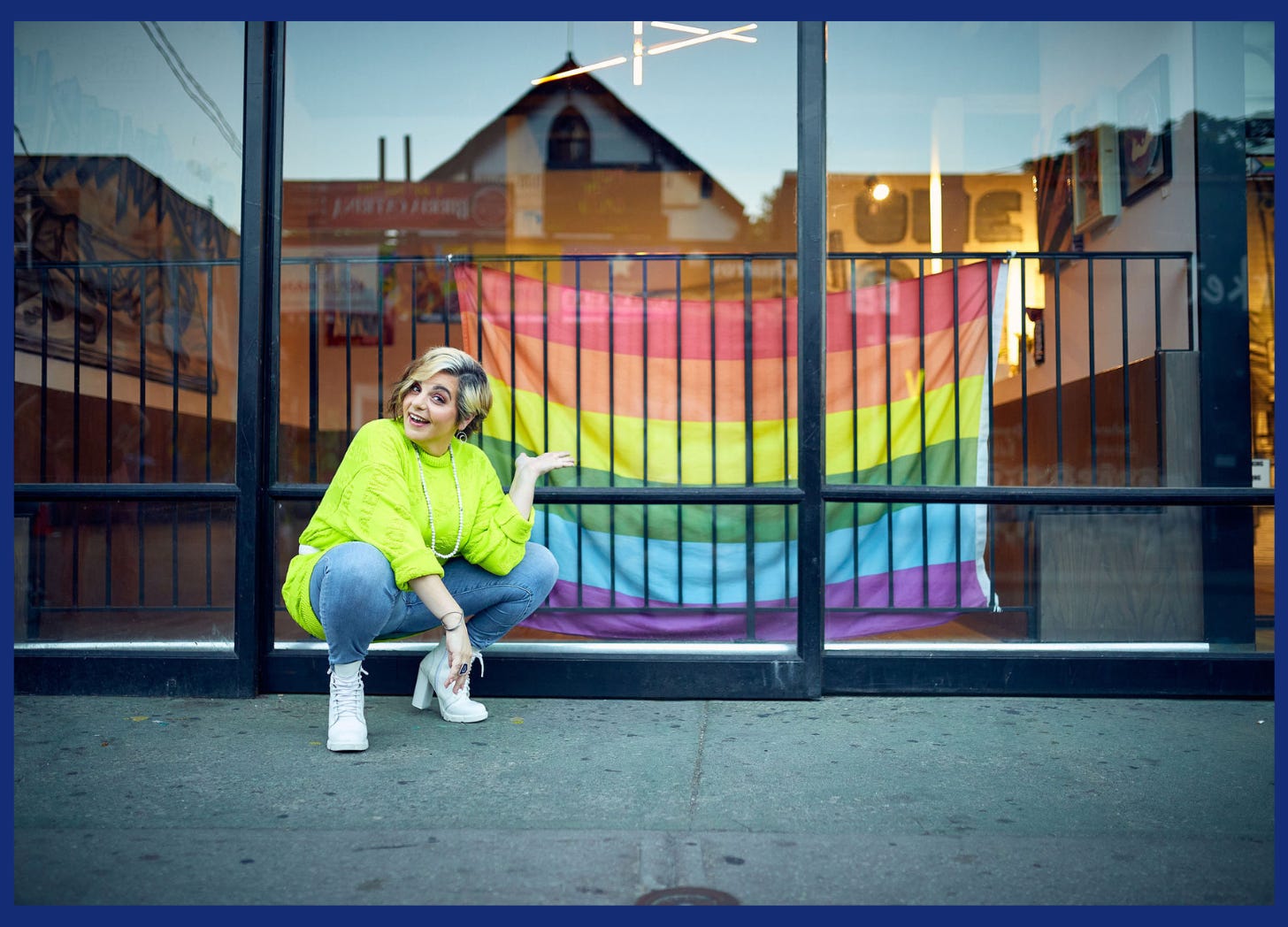 An Autistic woman poses in front of a rainbow flag. Unmasking Autism Blog: Coming Out...Again...and Again...Autistic Blog | Self-disclosure as an Autistic Woman