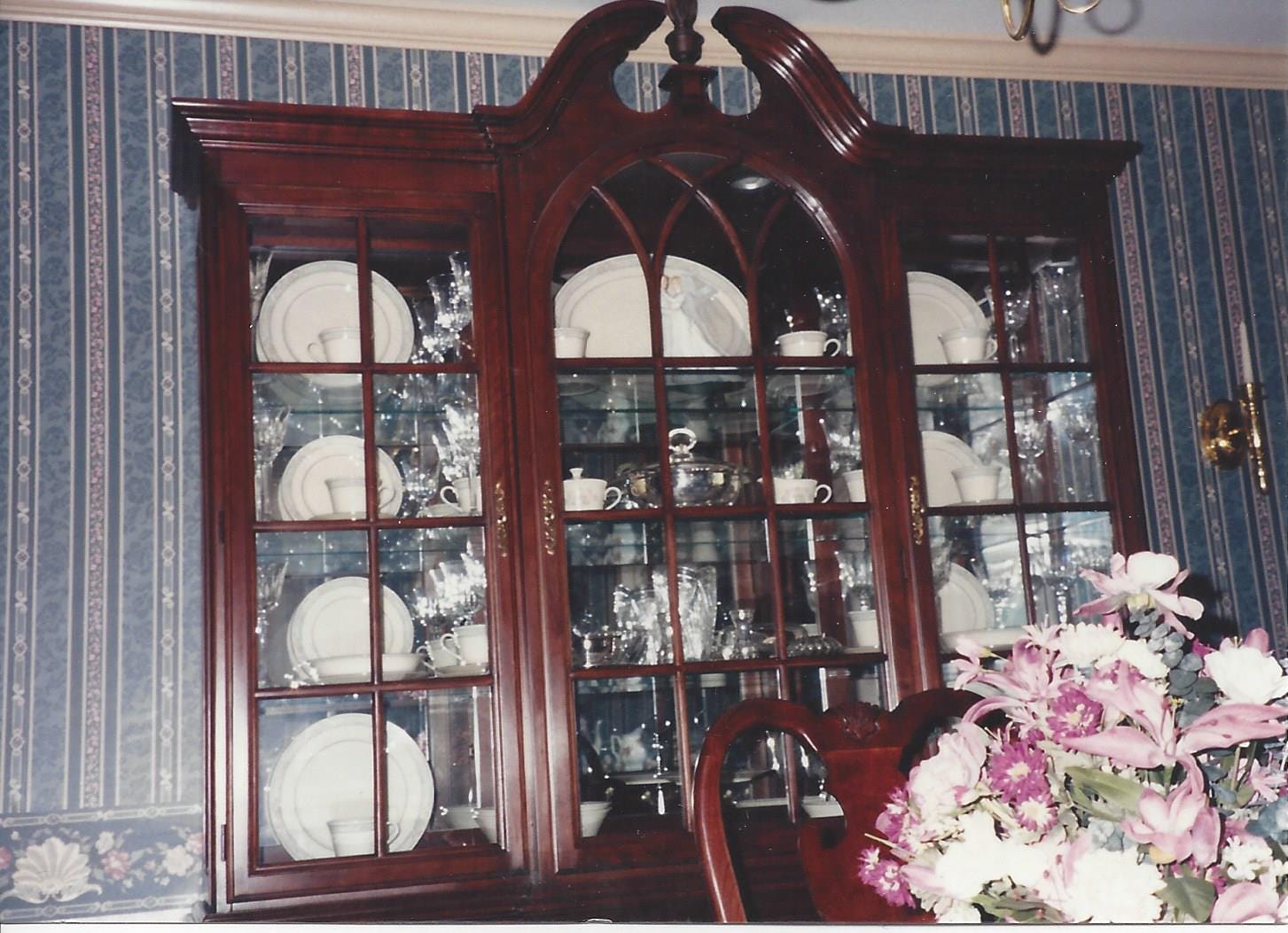 Close-up of a cherry Queen-Ann- style china closet with the good china visible inside