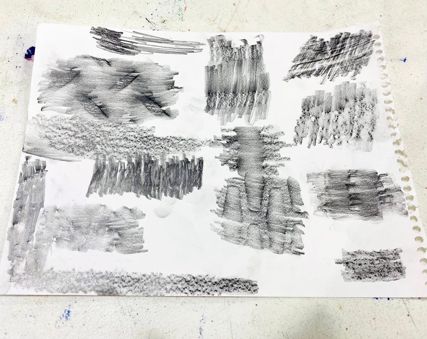 A white sheet of paper with different sections of graphite rubbings of materials including the table, chair, and wood.