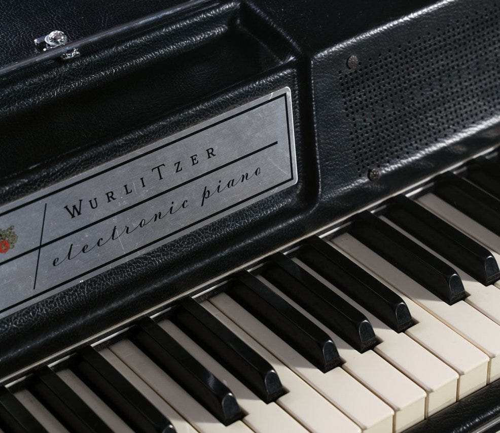 Closeup of a Wurlitzer 200a, showing the faceplate logo and two of the speaker screws.