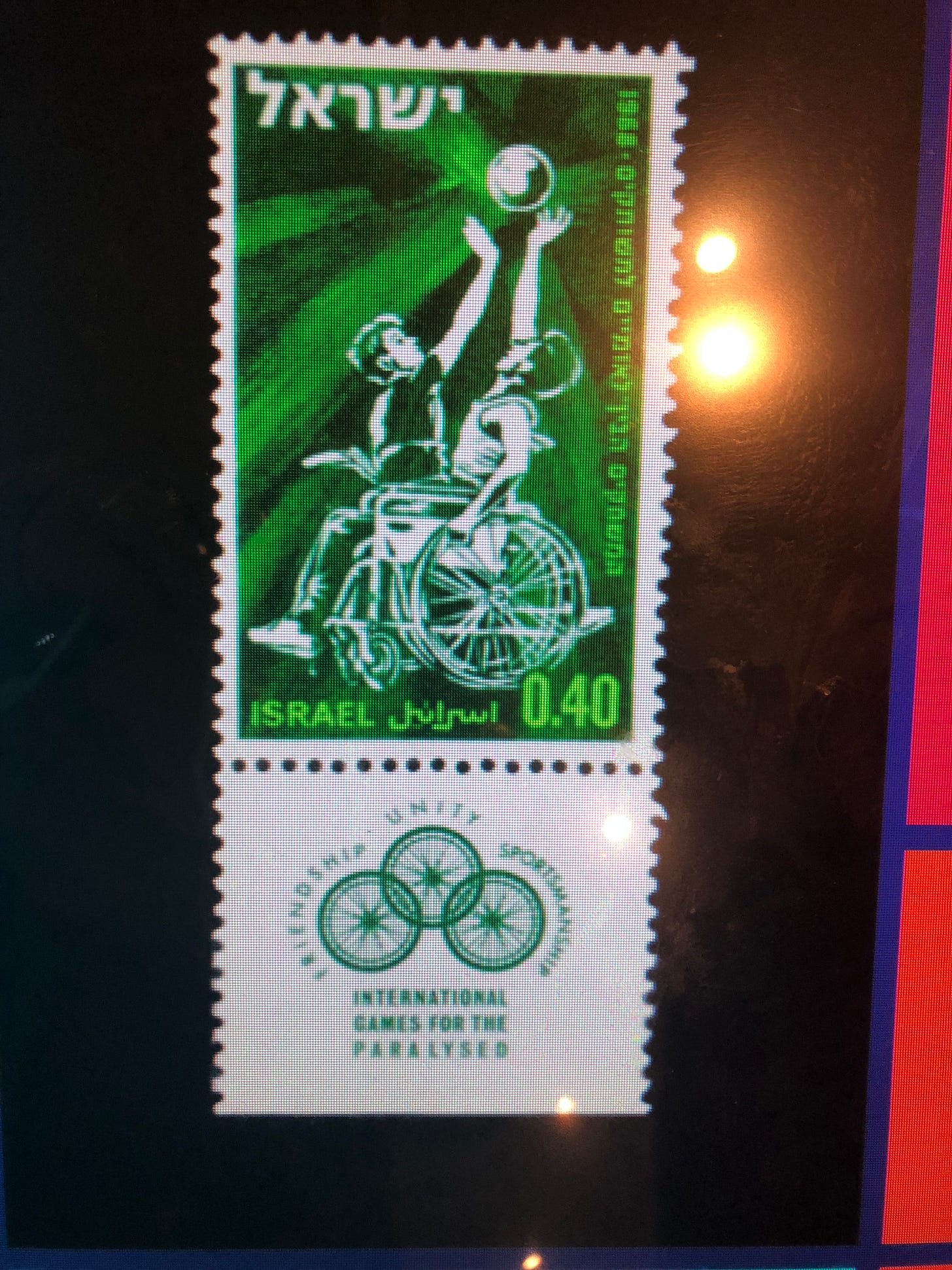 a green postage stamp showing a person in a wheelchair shooting a basketball
