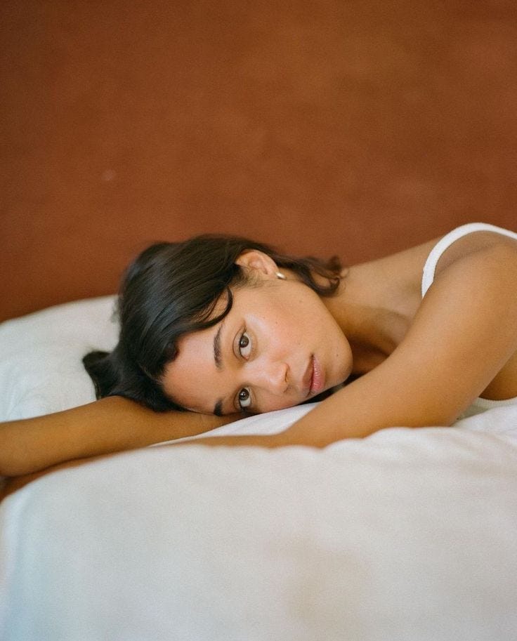 This may contain: a woman laying on top of a white bed