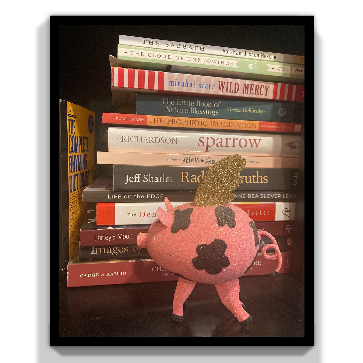 Photo of pig with wings in front of a stack of books.