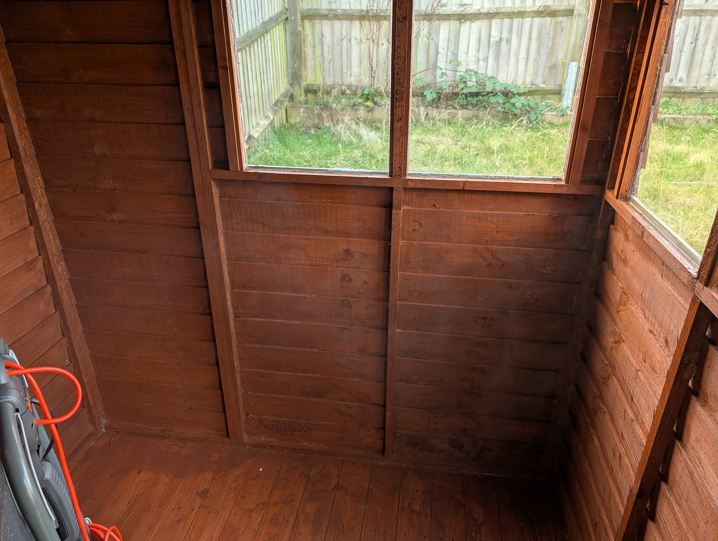 Shed wall after the brown paint has dried, showing a surprisingly pleasant, lighter finish.