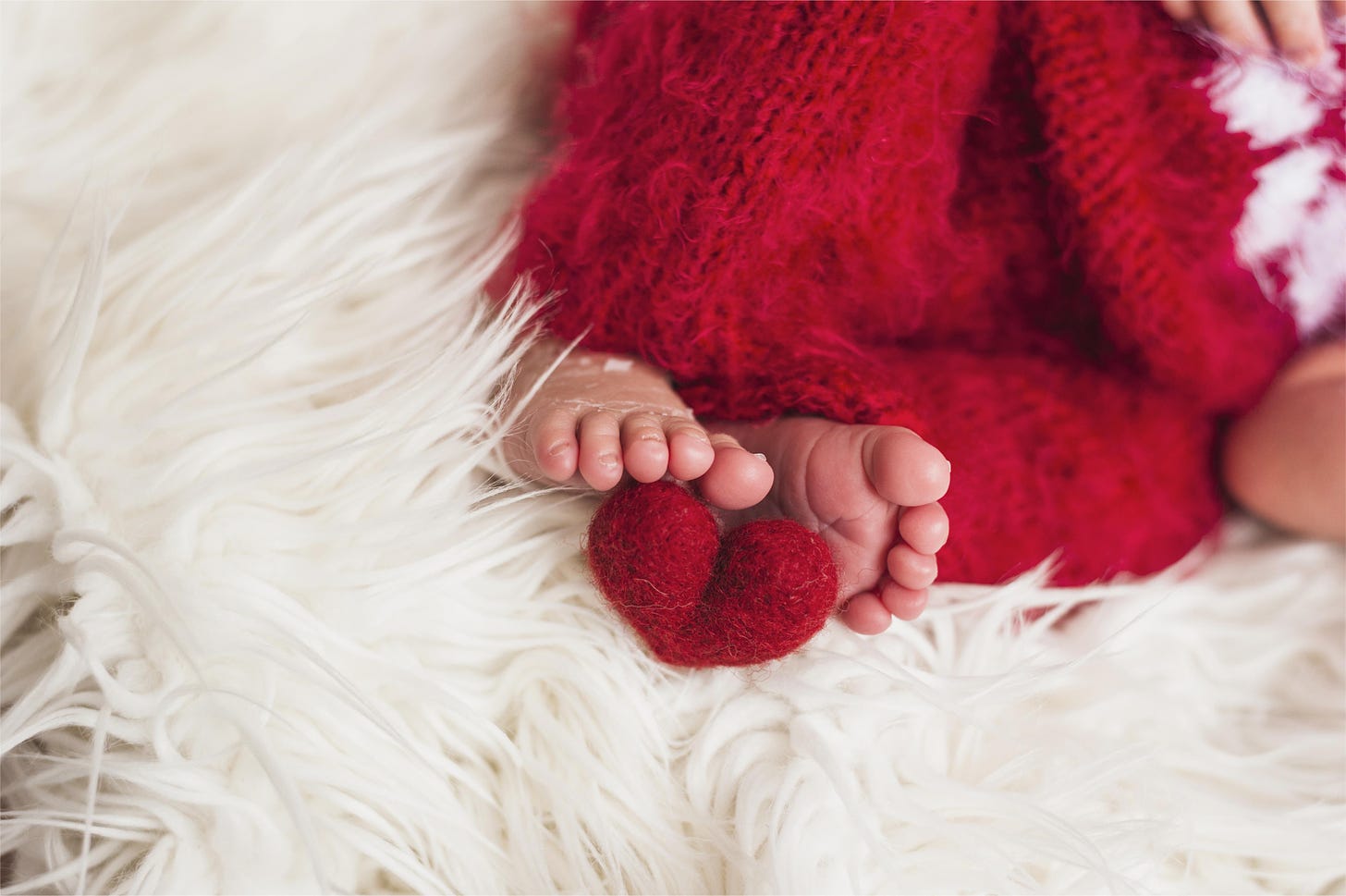 crop-baby-feet-with-red-heart-near