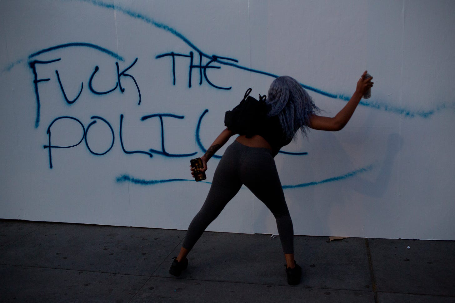 A protestor paints on a wall, May 31, 2020. (Photo by Andrew Lichtenstein/Corbis via Getty Images)