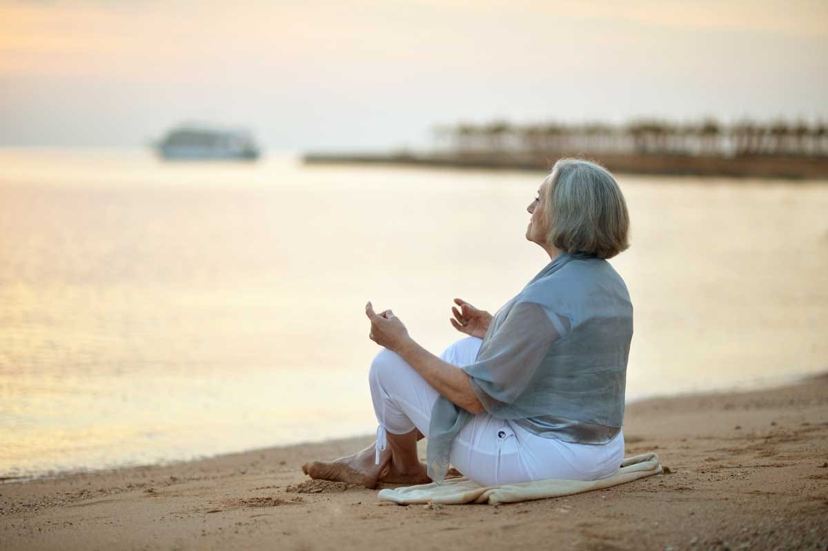 Mature woman meditating on the beach.