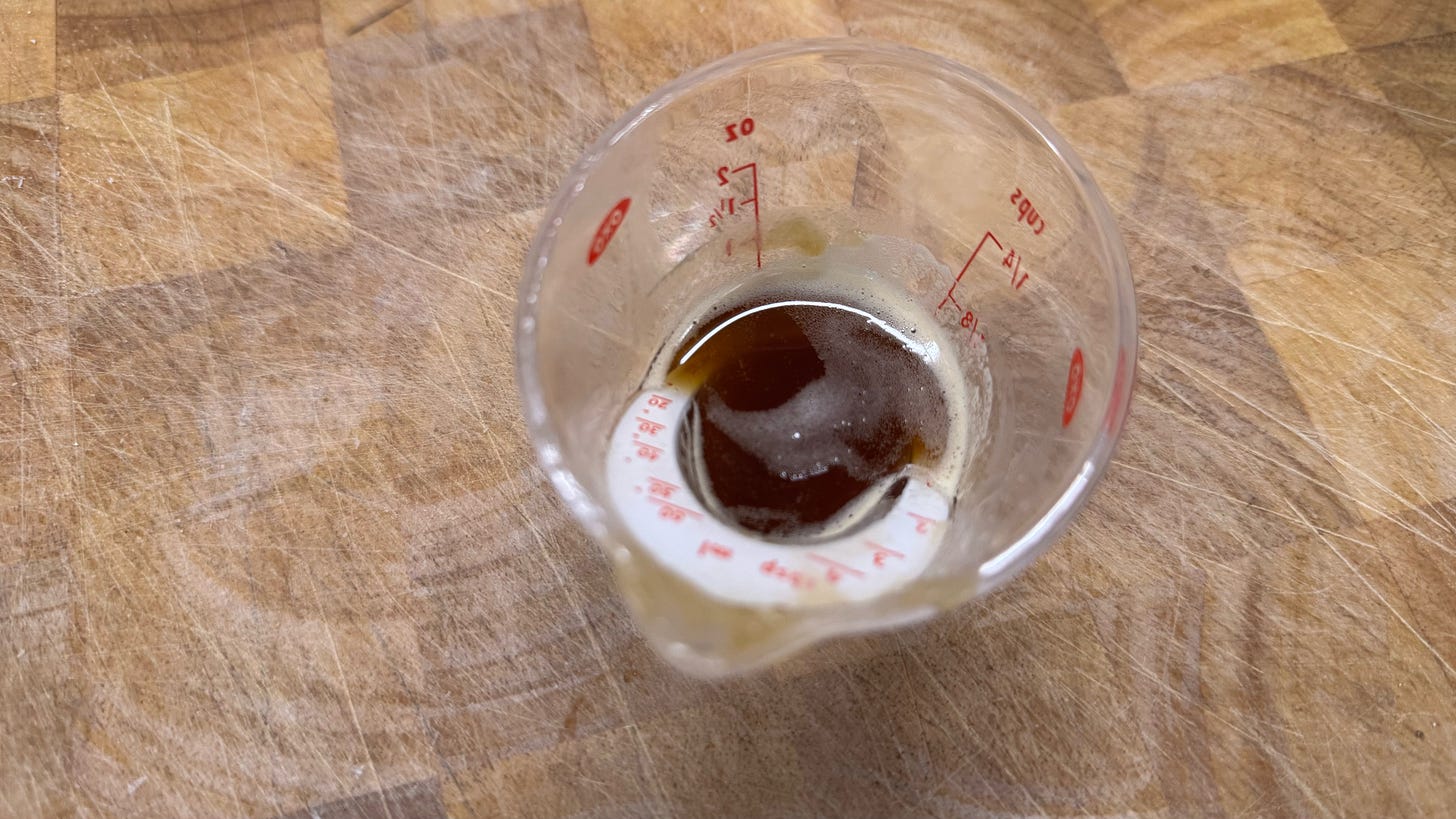 A small measuring cup containing some very, very dark brown butter.
