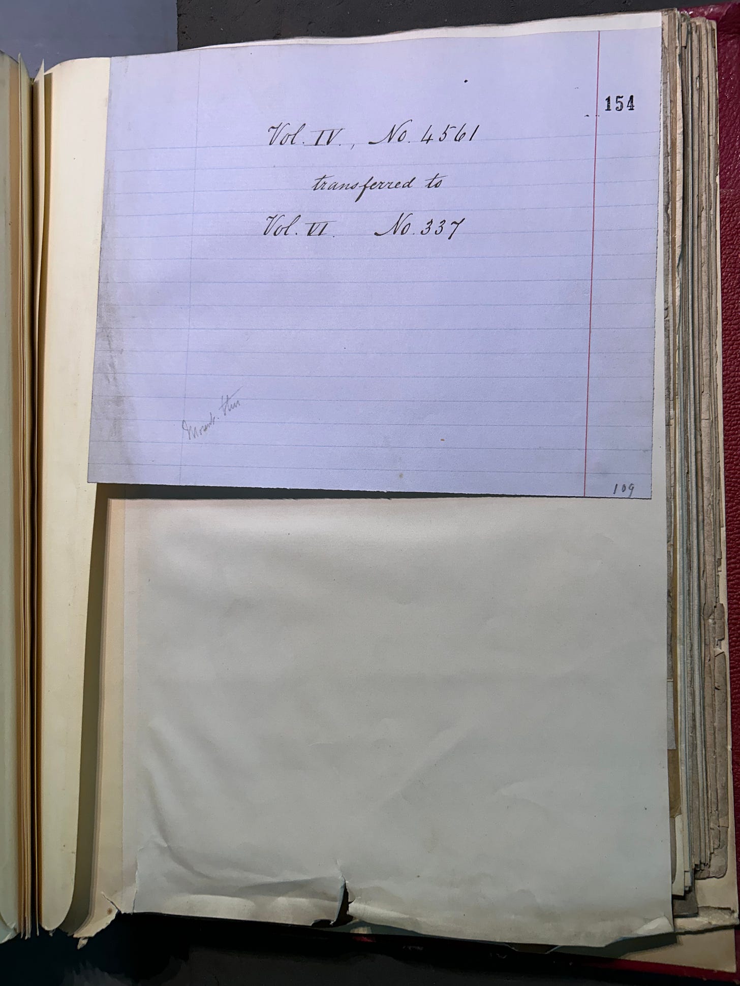 A handwritten note on a piece of line paper in a large bound book, indicating that a document has been removed and refiled at a later date.