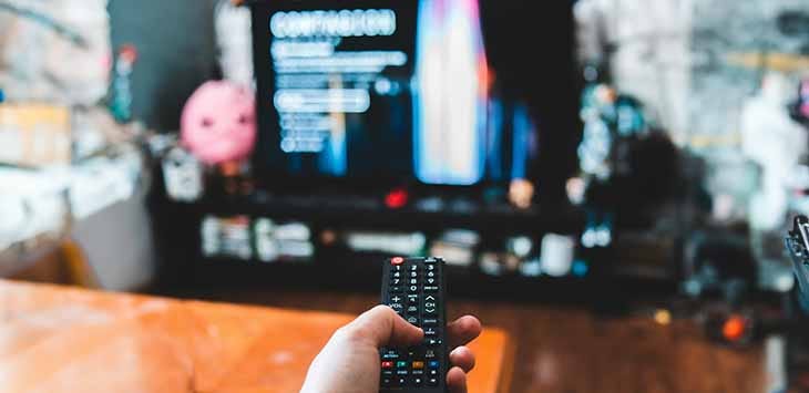 Photo of someone using a remote control to change the channel on a smart TV.