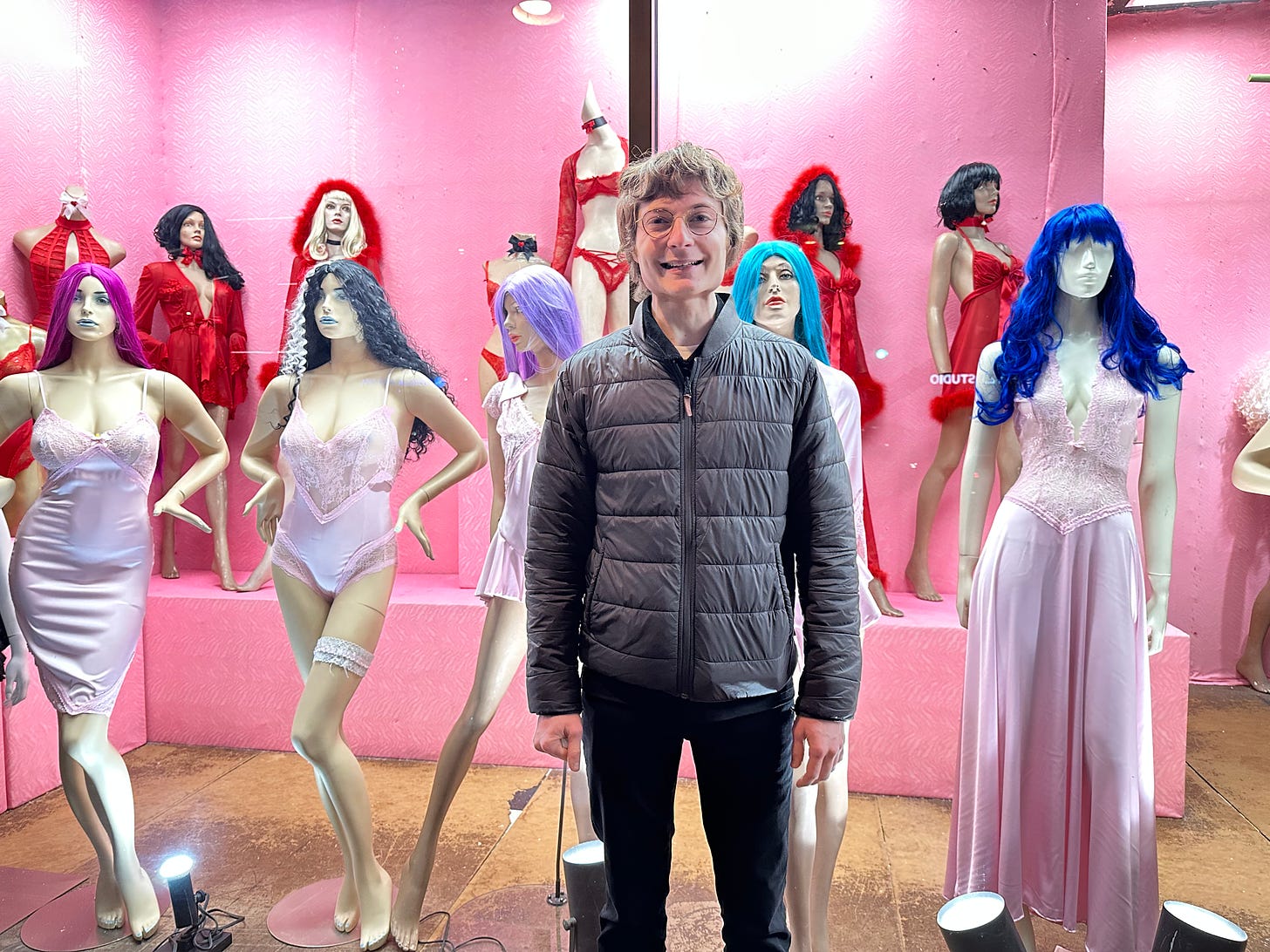 Me standing in front of a lingerie window display with a silly smile on my face.