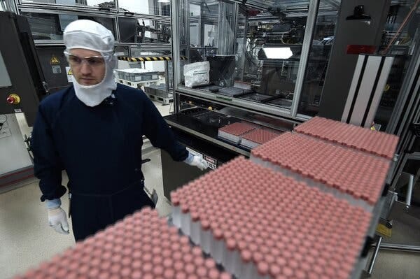 A person in a factory at a conveyor belt with red-capped insulin injector pens being produced.