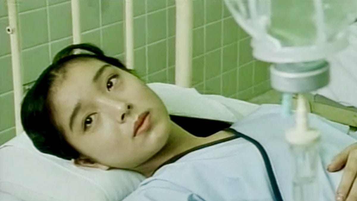 An image from Splatter: Naked Blood featuring Misa Aika laying in a hospital bed.