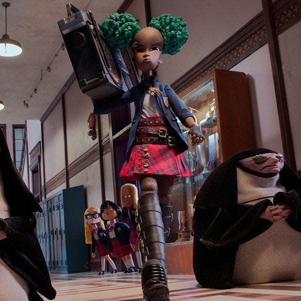 A still of Wendell & Wild: we see Kat, the protagaonist, who is a young Black girl with dyed green hair which she wears in two puffs. She is carrying a large boombox on one shoulder, and is rocking goth stack boots with her torn-up school uniform that she has customized herself to more fit her aesthetic. Around her, students look on in curiosity.
