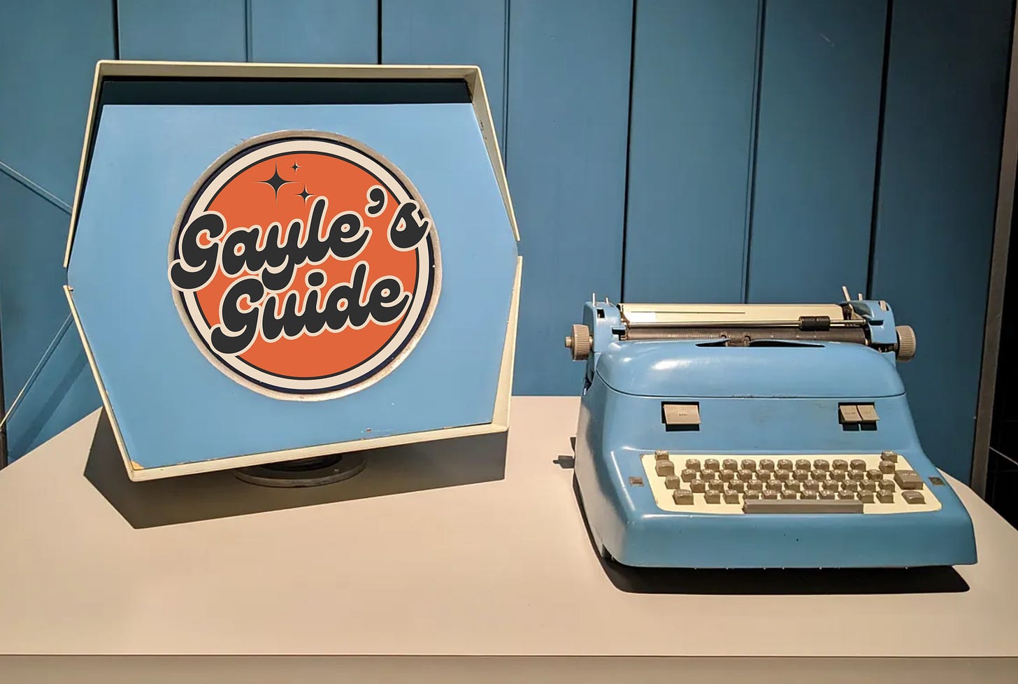 A 1959 PDP-1 computer with hexagon screen and typewriter style keyboard in soft blue. Gayle's Guide logo fits into the inner circle of the screen.