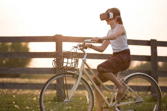 A girl wearing a VR helmet while riding a bike. This seems like a really bad idea.