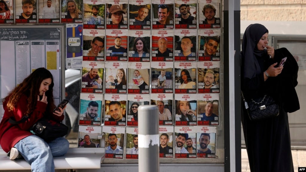 Women check their phones at a bus stop displaying portraits of Israeli hostages taken by Hamas militants during their Oct. 7, 2023, terror attack on Israel, in Jerusalem, Jan. 15, 2025.