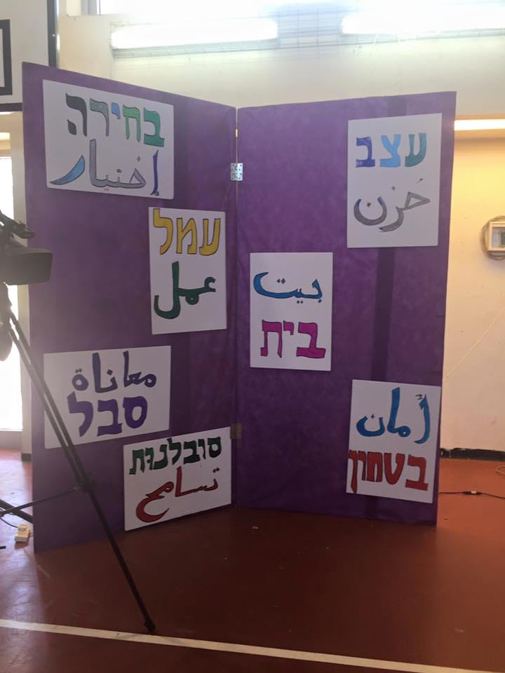Hebrew and Arabic words written in bright marker colors on poster board
