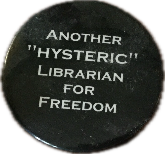 A black button with white words that say “Another ‘hysteric’ librarian for freedom.”