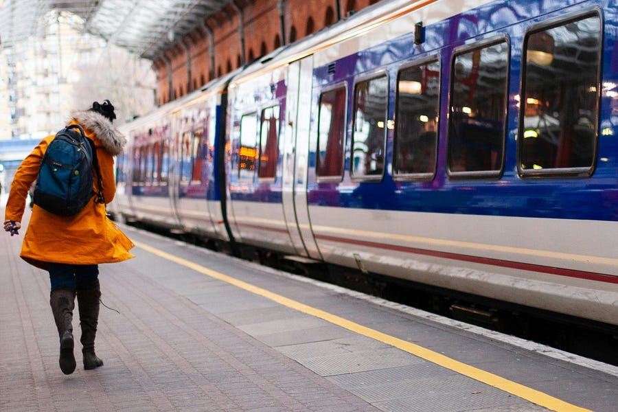 Woman in yellow coat running for the train.
