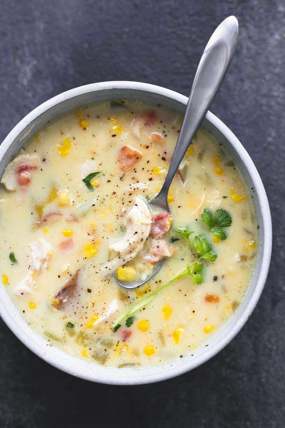 top view of slow cooker corn chowder with a spoon in a bowl.