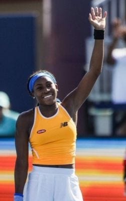 This may contain: a female tennis player raising her arm in the air