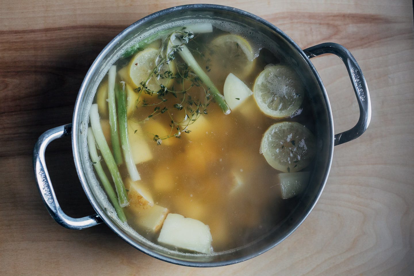 A pot of broth with vegetables. 