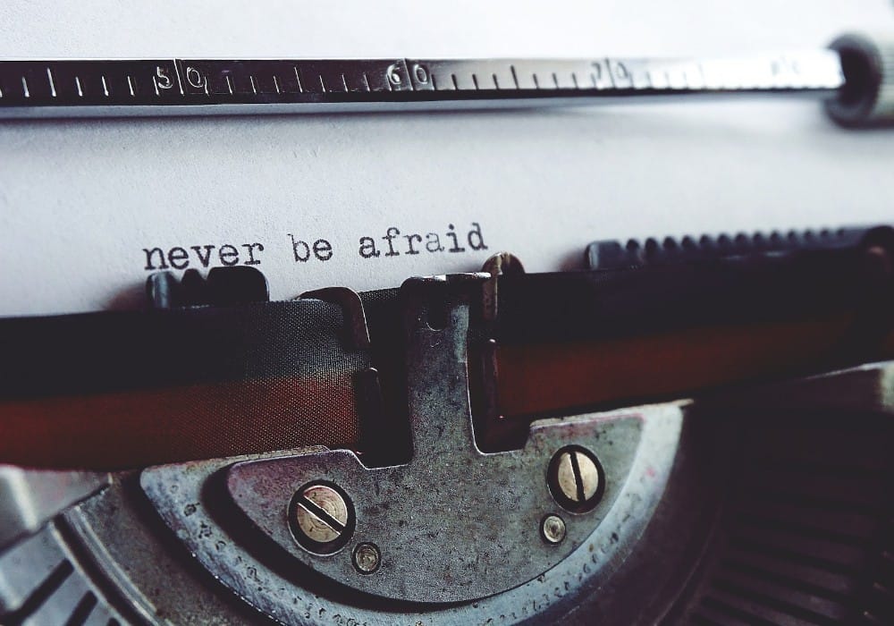 Typewriter with page inserted and text saying never be afraid it's low vibration