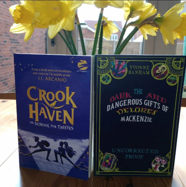 Crookhaven by J.J. Arcanjo and The Dark and Dangerous Gifts of Delores Mackenzie - two book covers on table with daffodils behind
