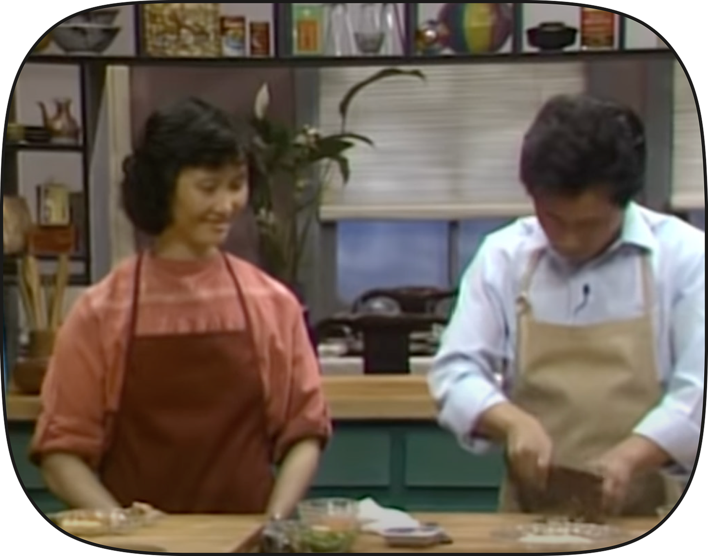 In this screenshot, Martin Yan chops ingredients with a cleaver. To his left is dim sum cook Mei Yan from Yank Sing.